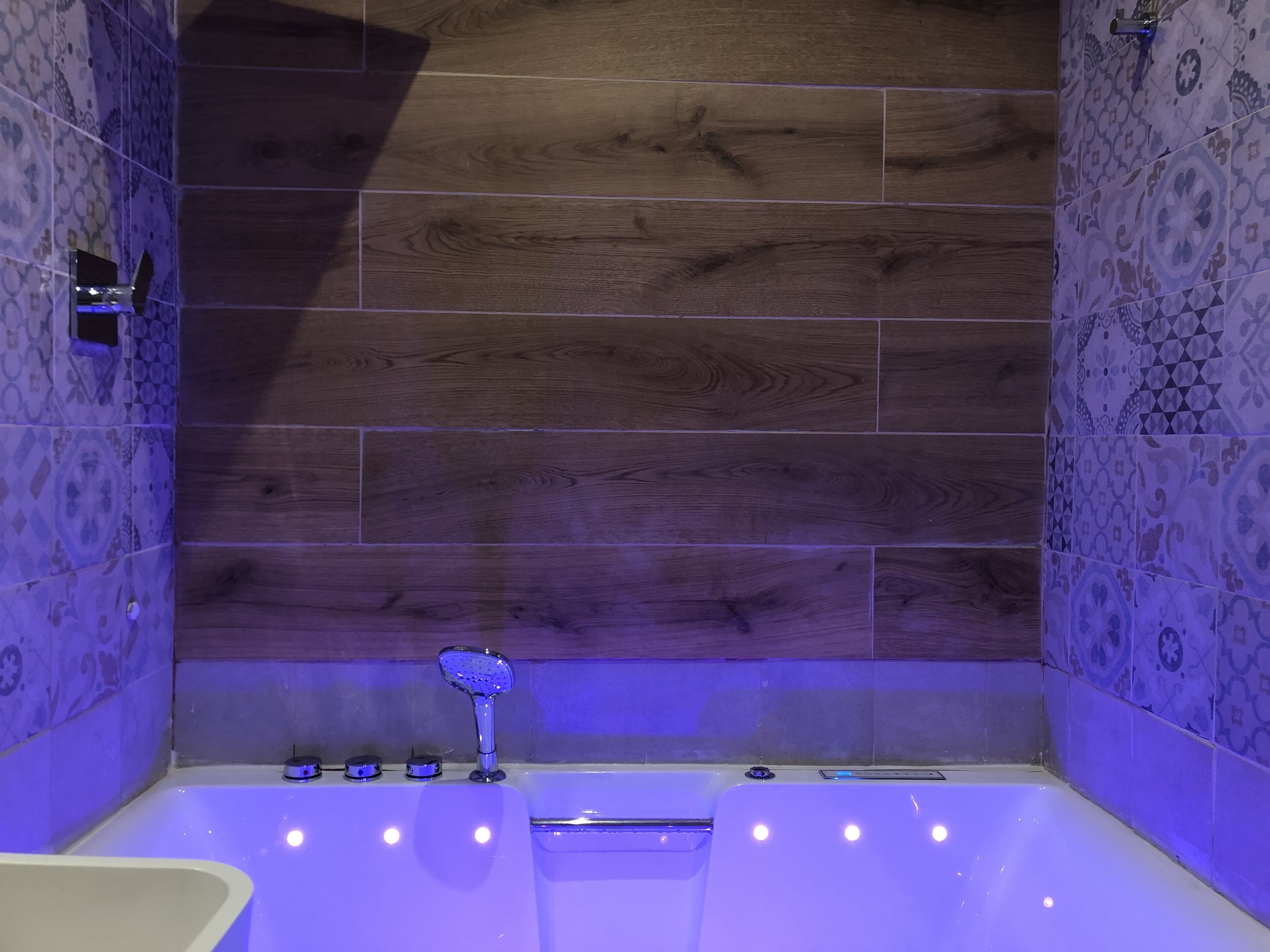 Un bagno moderno con una parete in legno, una vasca da bagno e un’area doccia.