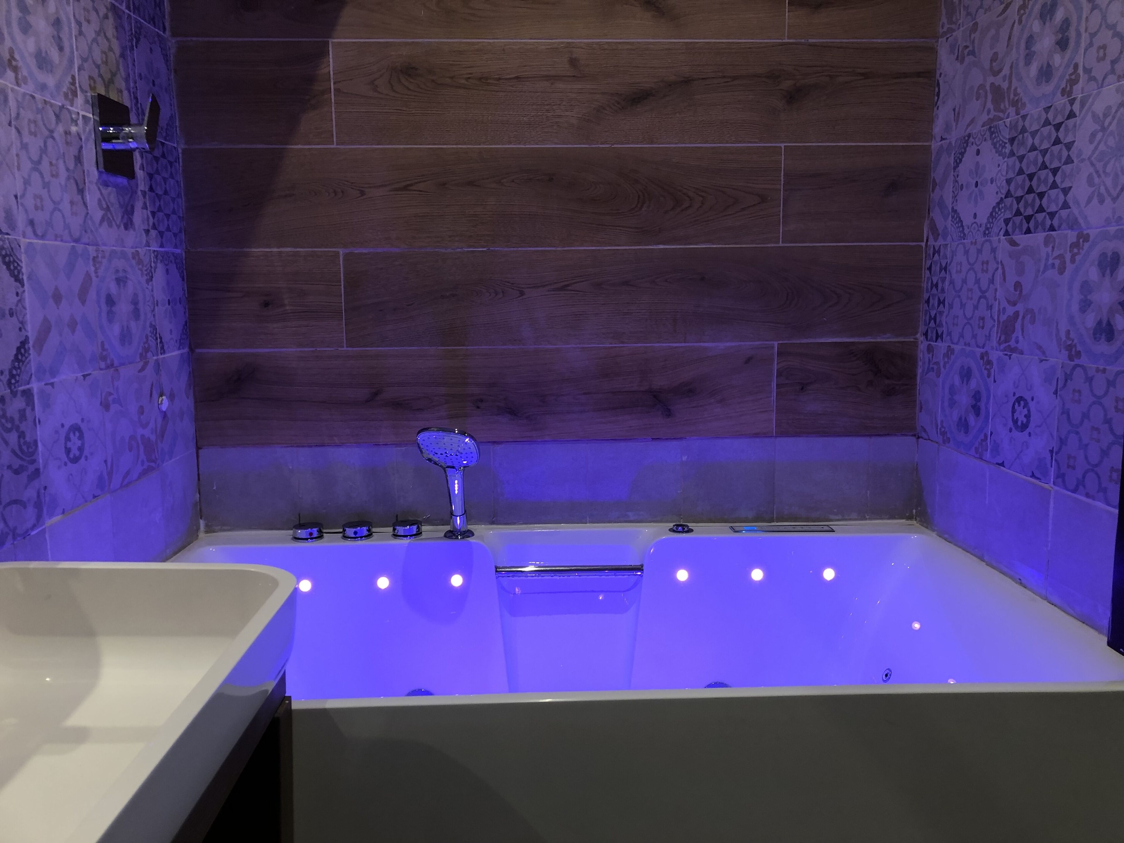 A modern bathroom with a freestanding bathtub, a handheld showerhead, and a wall-mounted control panel.