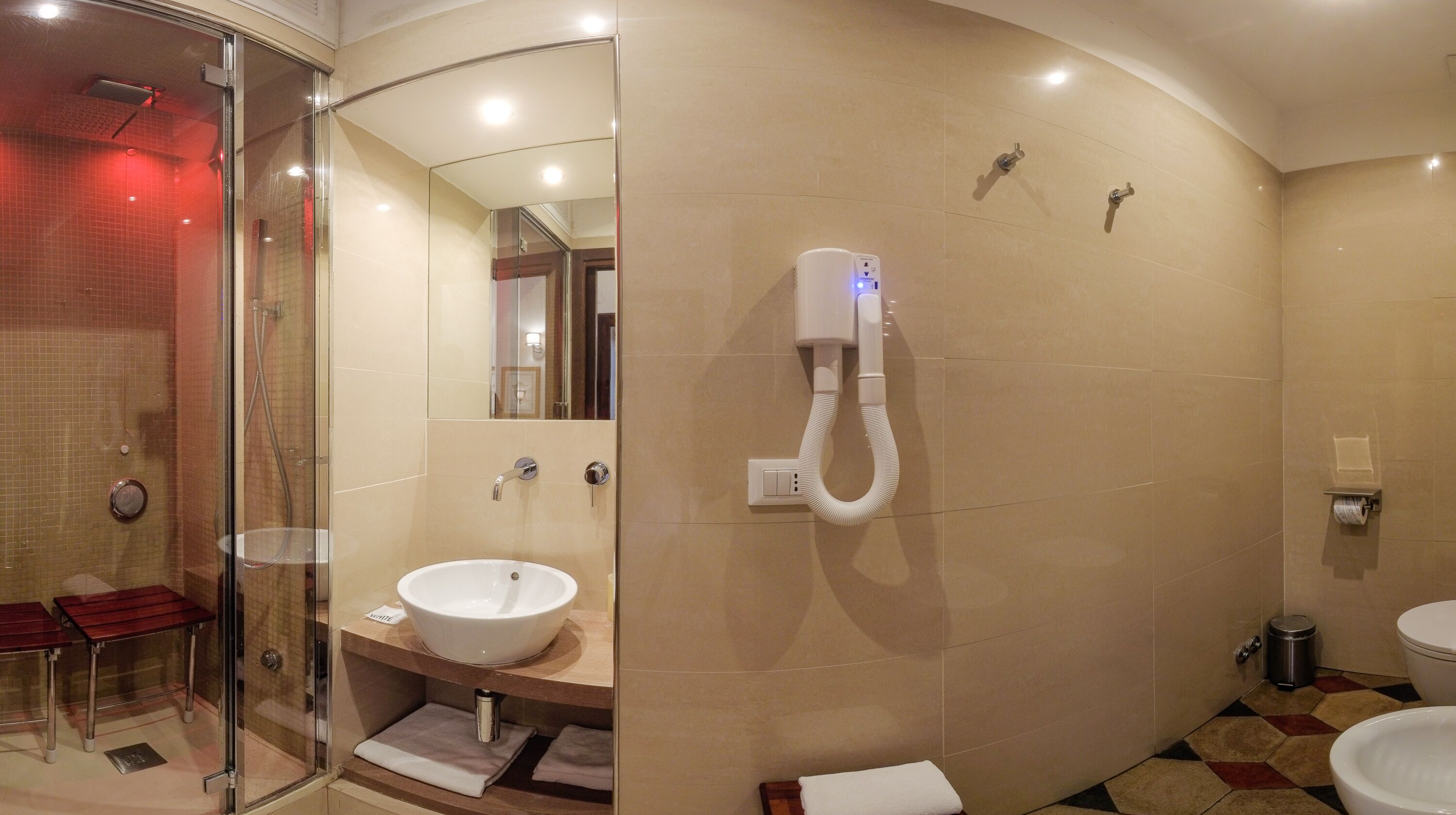 A modern bathroom with a glass shower enclosure, a sink with a mirror, and a toilet.