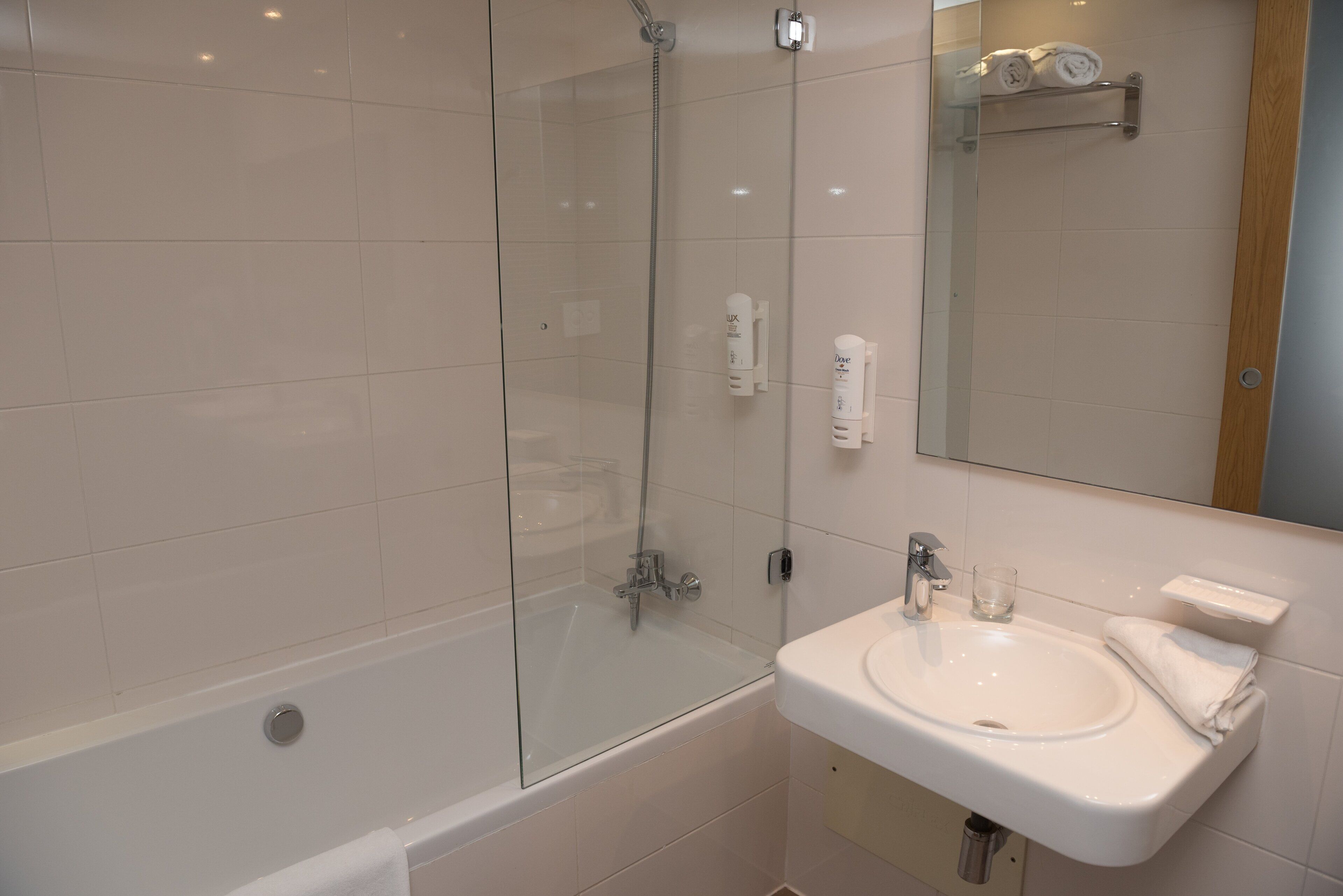 A modern bathroom with a glass-enclosed shower, a white sink, and a mirror.