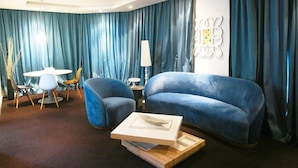 Una sala de estar moderna con un sofá azul, una mesa de centro y un comedor con sillas y una mesa.