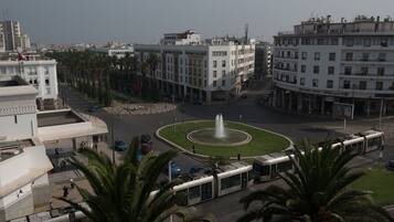 Una plaza urbana con una fuente, palmeras y edificios modernos.