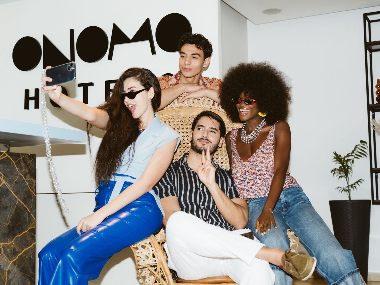 Un grupo de personas sentadas en una silla en una habitación con un letrero que dice 'ONOMO HOTEL'.