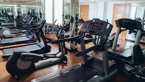 Un gimnasio con cintas de correr, bicicletas estáticas y una máquina de pesas.