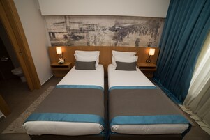 Una habitación de hotel con dos camas, un mural grande en la pared y vistas a la ciudad.