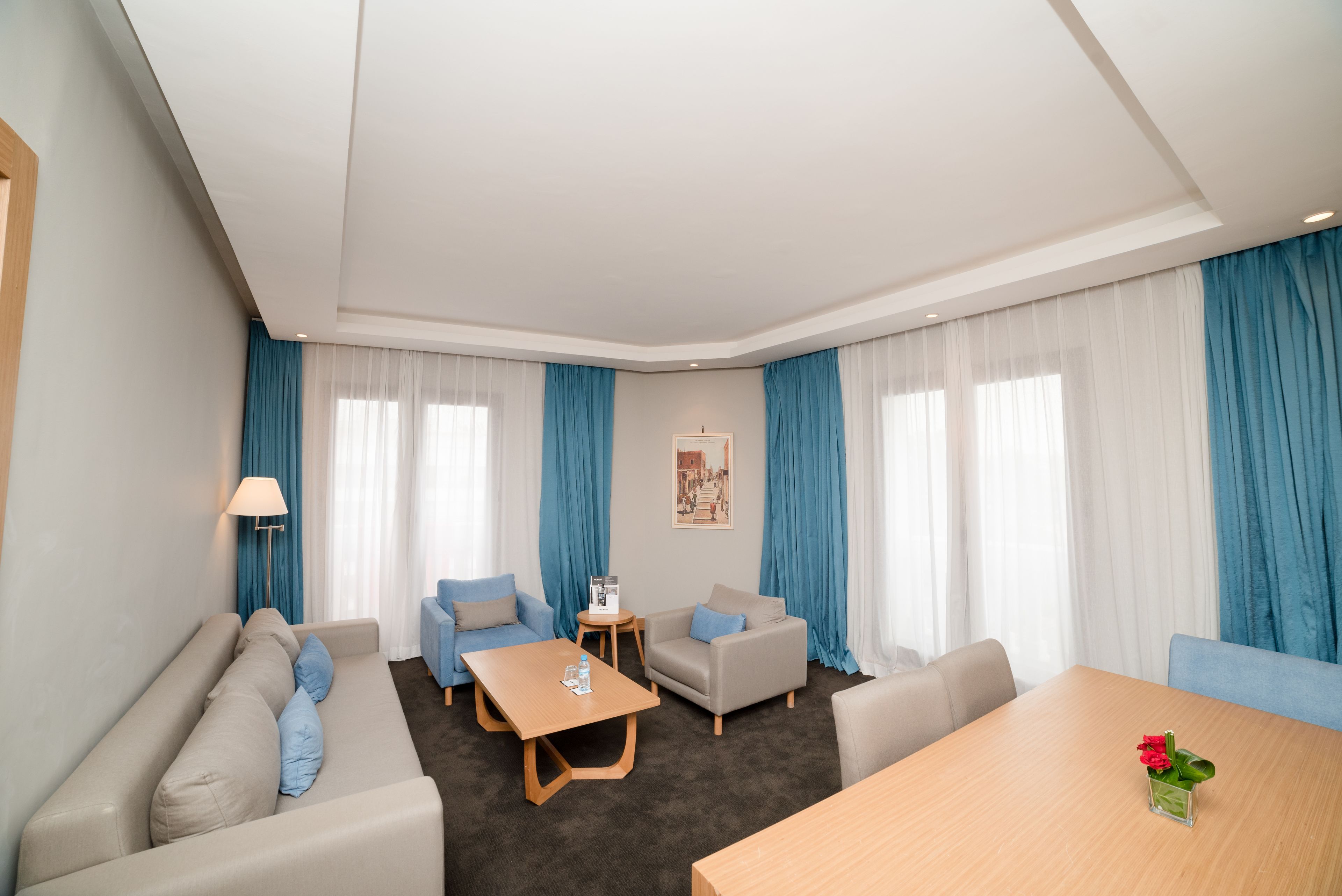 Una habitación de hotel moderna con sofá, dos sillones, una mesa baja y una mesa de comedor.