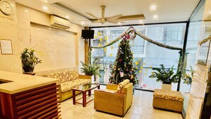 A modern hotel lobby with a reception desk, sofas, and a Christmas tree. - Paradise Hotel (Da Nang)