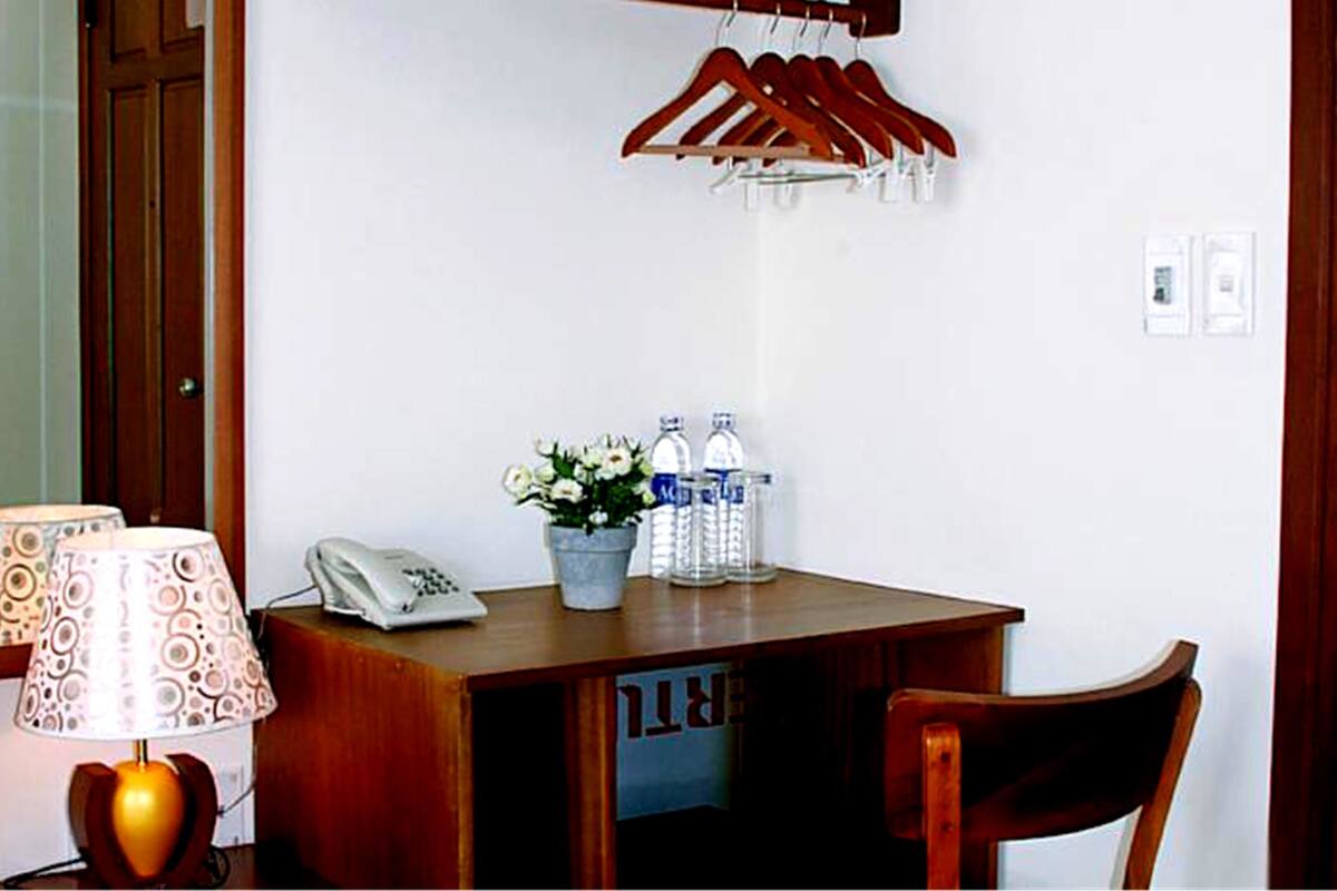 A wooden desk with a lamp, a telephone, a potted plant, and two water bottles.