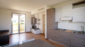A modern kitchen with a built-in oven, a sink, and a dining area with a table and chairs. - Residence Le Querce (Cernusco sul Naviglio)