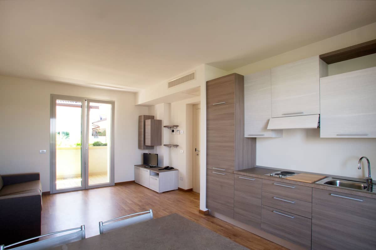 A modern kitchen with a built-in oven, a sink, and a dining area with a table and chairs.