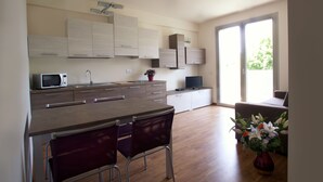 A modern kitchen with a dining area, wooden cabinets, a microwave, and a potted plant. - Residence Le Querce (Cernusco sul Naviglio)