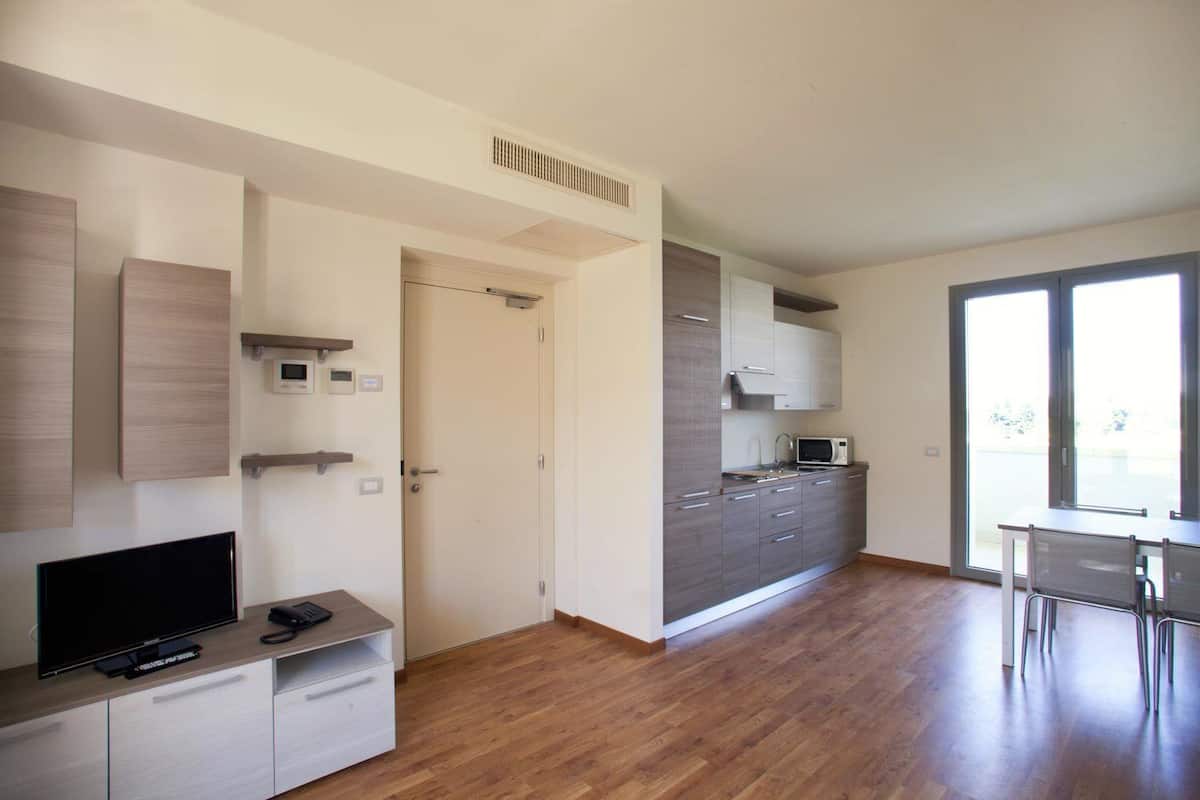 A modern kitchen with grey cabinets, a microwave, and a dining area with a table and chairs.