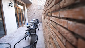 A narrow outdoor patio with brick walls, several tables and chairs, and a small American flag. - Hotel 27 (Tbilisi)