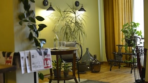 A living room with a wooden table, a large potted plant, a vase, and a bookshelf. - Hotel 27 (Tbilisi)