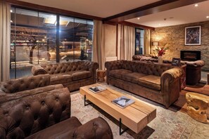 A cozy living room with leather sofas, a wooden coffee table, and a stone fireplace.