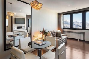 Una sala de estar moderna con comedor, televisor de pantalla plana y un ventanal con vistas.