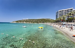 Une plage avec une eau claire, un rivage sablonneux et un bâtiment à étages.