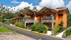 A two-story building with a stone facade, multiple balconies, and a paved driveway. - Arenal Springs Resort (La Fortuna)