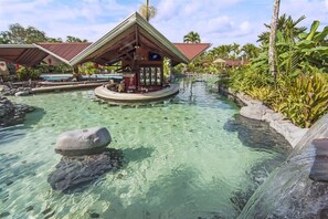 A tropical resort with a clear pool, a bar area, and lush greenery. - Arenal Springs Resort (La Fortuna)