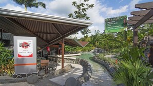 A restaurant named 'Sakura Sushi Bar' with a covered outdoor seating area, a stone pathway, and a small pond. - Arenal Springs Resort (La Fortuna)