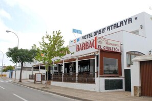 Un bâtiment sur lequel on peut lire les enseignes « Hotel Oasis Atalaya » et « Barbacel Chuleton ».