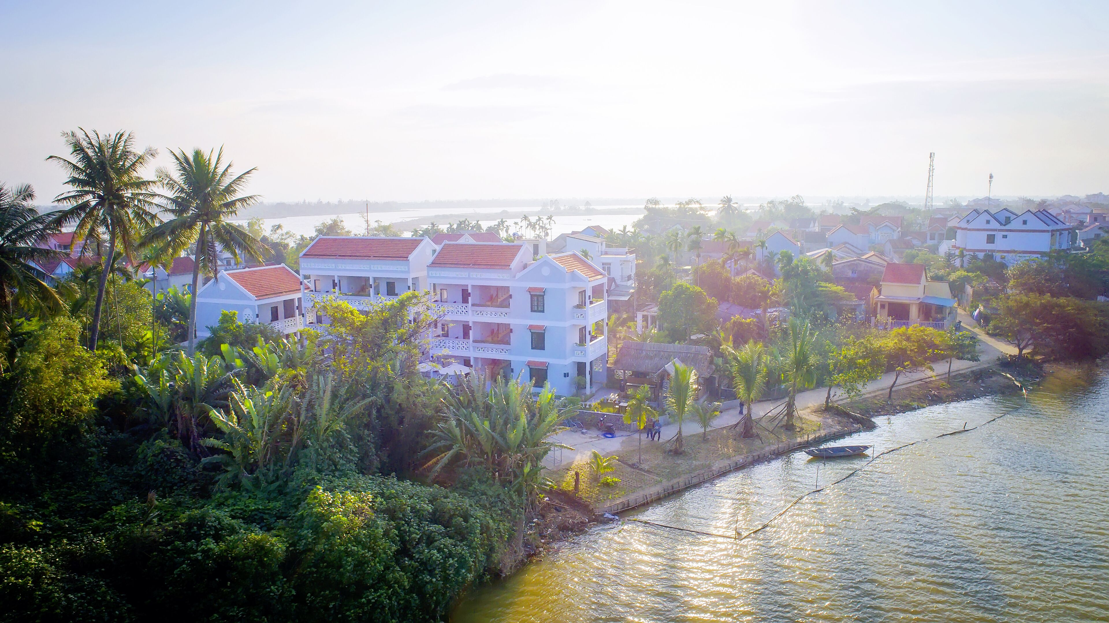 A riverside residential area with multi-story buildings, lush greenery, and a calm river.