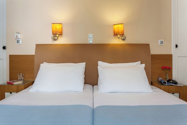 A double bed with white linens, two bedside tables, and wall-mounted lamps.