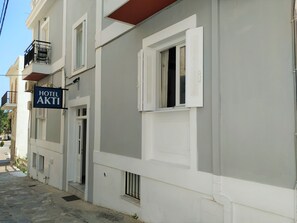 A hotel building with a sign reading 'HOTEL AKTI,' a balcony with a metal railing, and a window with shutters.