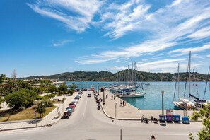 Un port de plaisance avec des bateaux amarrés, une route menant à l’eau et un paysage vallonné en arrière-plan.