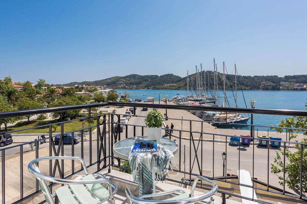 A balcony with a view of a marina, a table with a plant, and a chair.