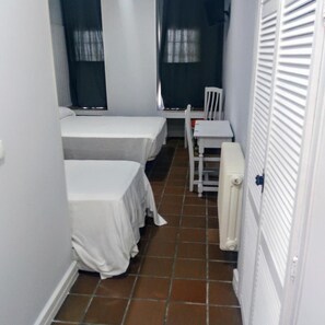 Een kleine kamer met twee bedden, een tafeltje en een stoel.