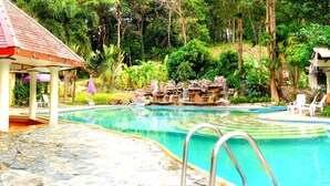 A swimming pool with a waterfall feature, surrounded by lush greenery and two small gazebos. - Koh Chang Resort Spa (Ko Chang)