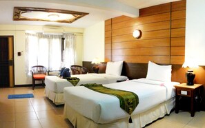 A hotel room with two beds, a wooden headboard, a nightstand, a chair, and an air conditioning unit. - Koh Chang Resort Spa (Ko Chang)