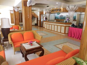 A reception area with a reception desk, a sofa, a table with a vase, and a lamp. - Koh Chang Resort Spa (Ko Chang)