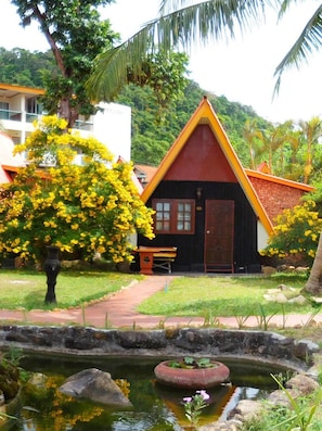 A traditional house with a red roof and yellow trim, surrounded by lush greenery and a small pond. - Koh Chang Resort Spa (Ko Chang)