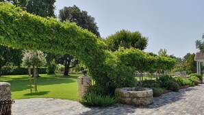 A paved pathway with stone bollards and a bench, surrounded by lush greenery and trees. - Domaine de Larchey & son restaurant - Bordeaux Sud (Saint-Medard-d'Eyrans)