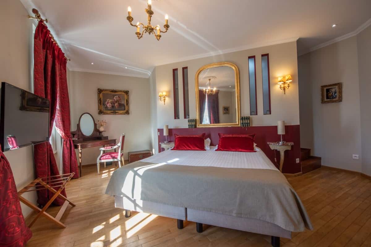 Un dormitorio con una cama grande, un escritorio, una silla, un espejo y una araña.
