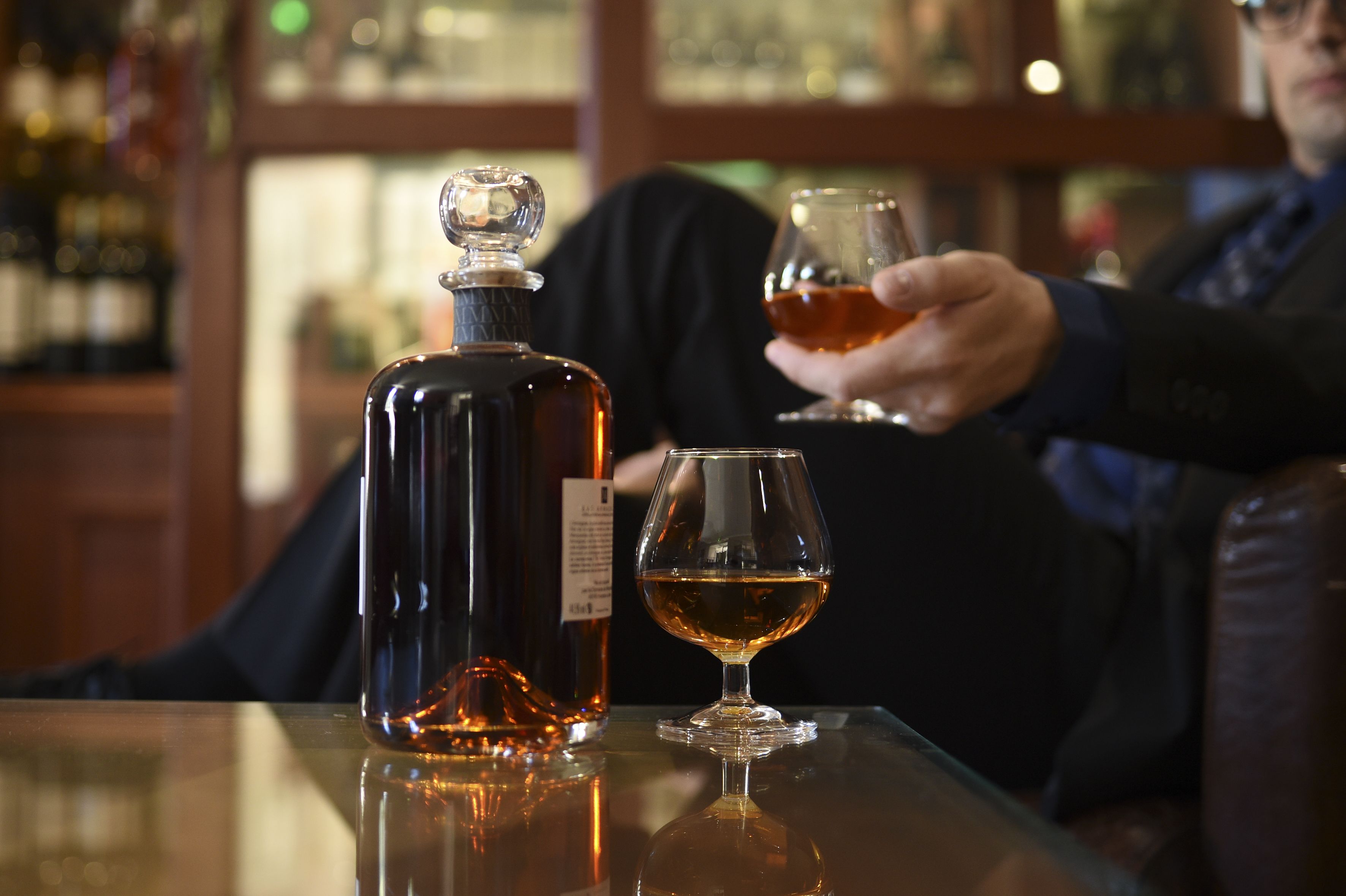 Une bouteille de whisky et un verre sur une table, dans un bar.
