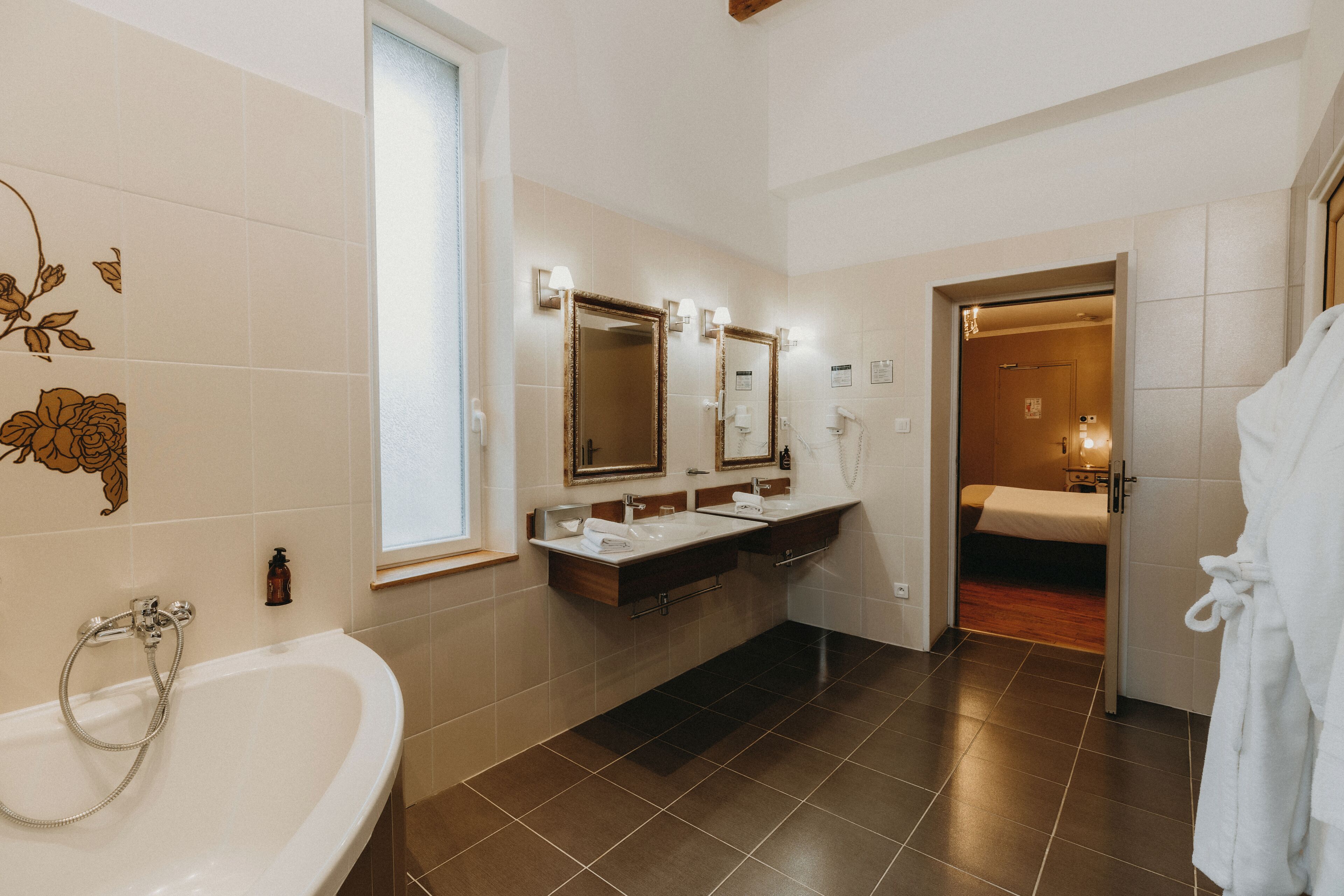 Un baño moderno con bañera, dos lavamanos y un espejo.