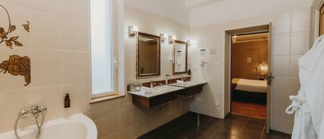 A modern bathroom with a bathtub, two sinks, and a mirror.