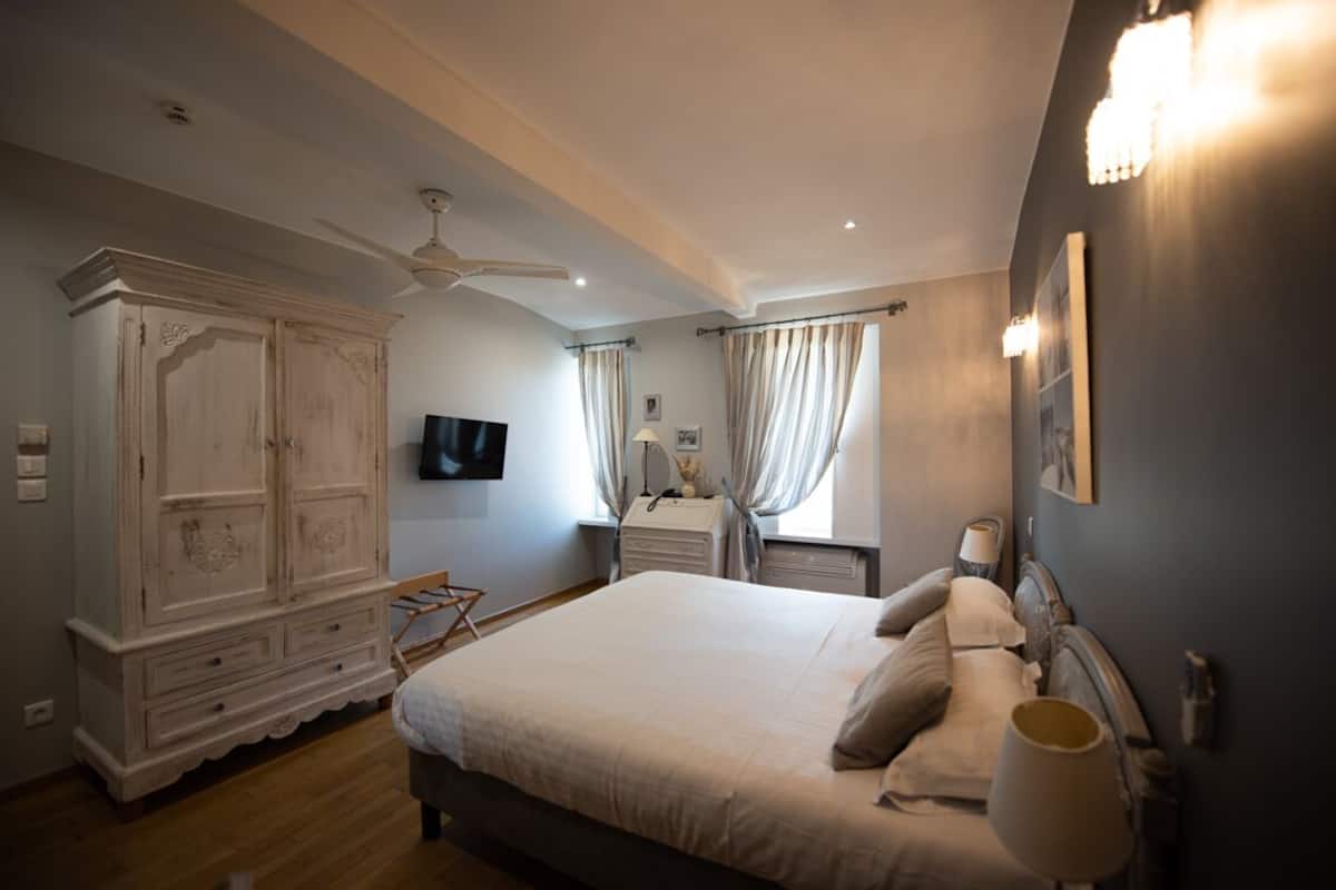Un dormitorio con una cama grande, un armario, un escritorio y un ventilador de techo.