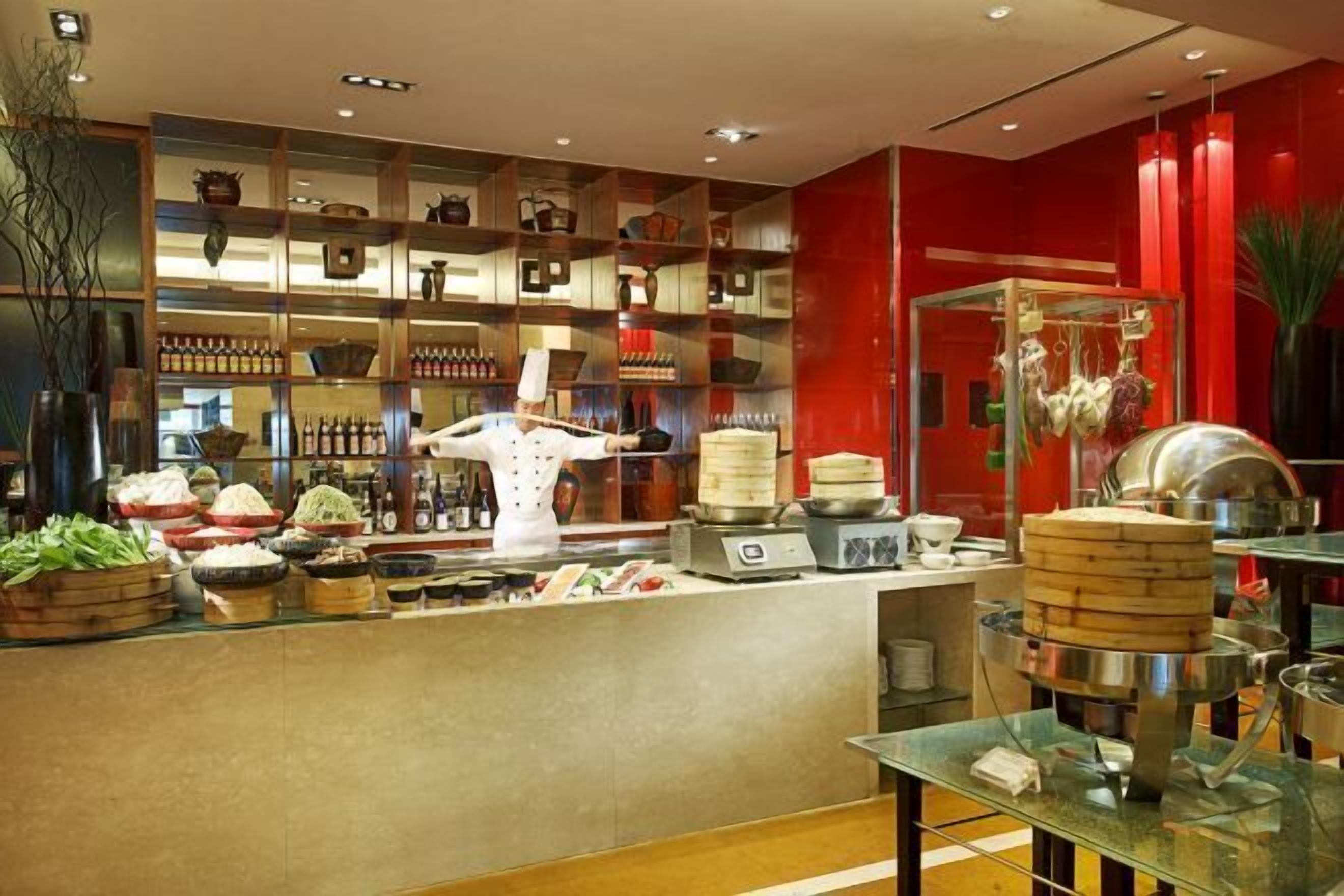 Una cocina moderna con un chef, diversos utensilios de cocina y una exhibición de alimentos.