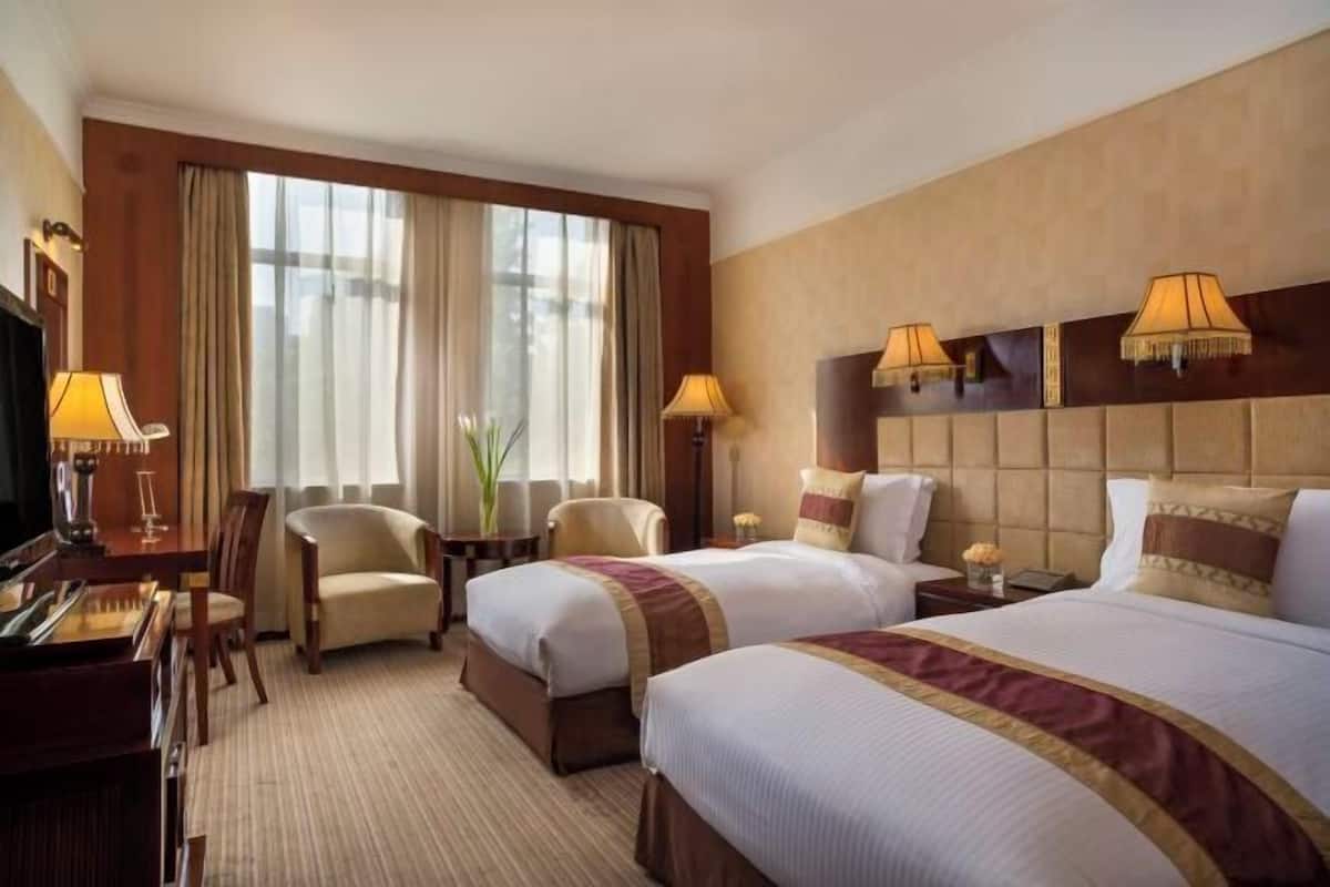 Una habitación de hotel con dos camas, un escritorio, una silla y un televisor.