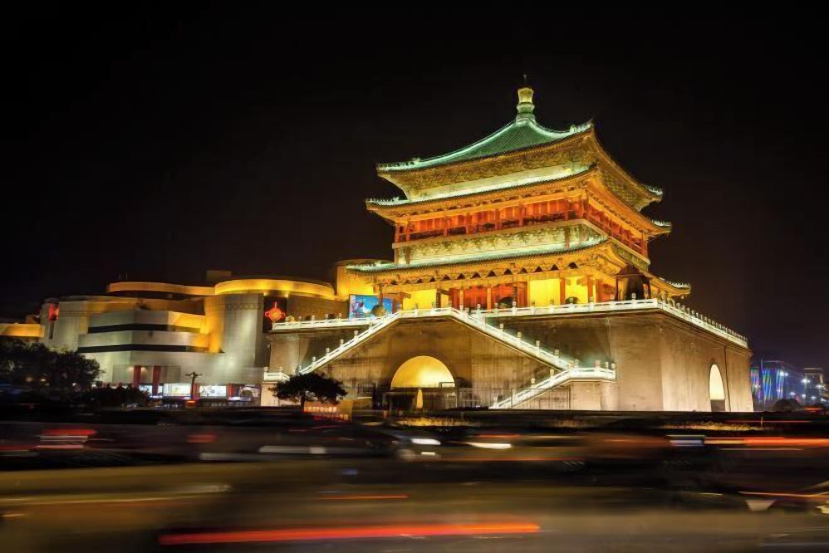 Um edifício tradicional com vários níveis, entrada destacada e uma ponte que o leva, cercado por construções modernas.