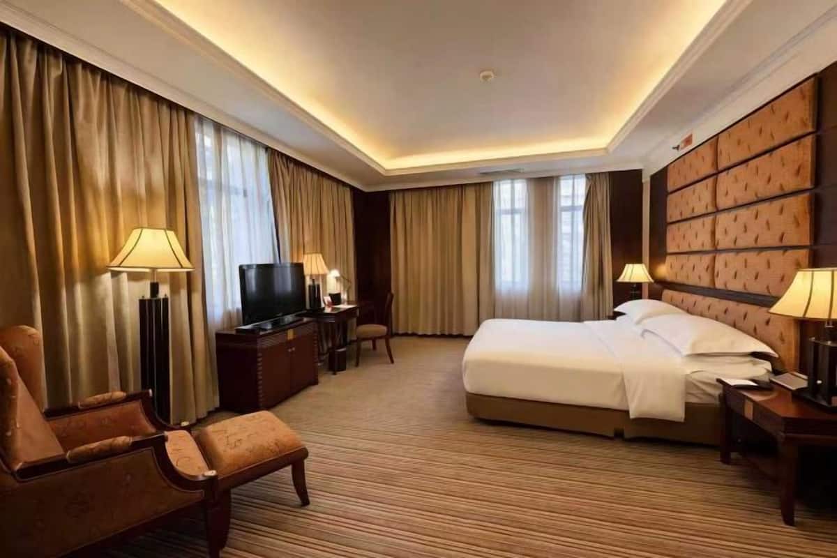 Una habitación de hotel con una cama grande, un escritorio, un televisor y dos lámparas.