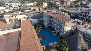 A multi-story hotel with a rooftop pool, surrounded by other buildings and palm trees. - Vallarta SOL (Puerto Vallarta)