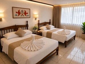 A hotel room with two beds, each with a towel arrangement, a nightstand with a lamp, a floral decoration on the wall, and a large window with curtains. - Vallarta Sol (Puerto Vallarta)