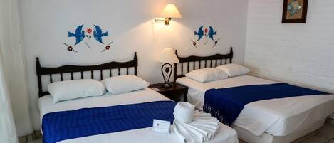 A hotel room with two beds, a nightstand, a lamp, and wall art.