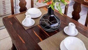 A dining area with a table set for two, a vase with flowers, and a television in the background. - Vallarta Sol (Puerto Vallarta)