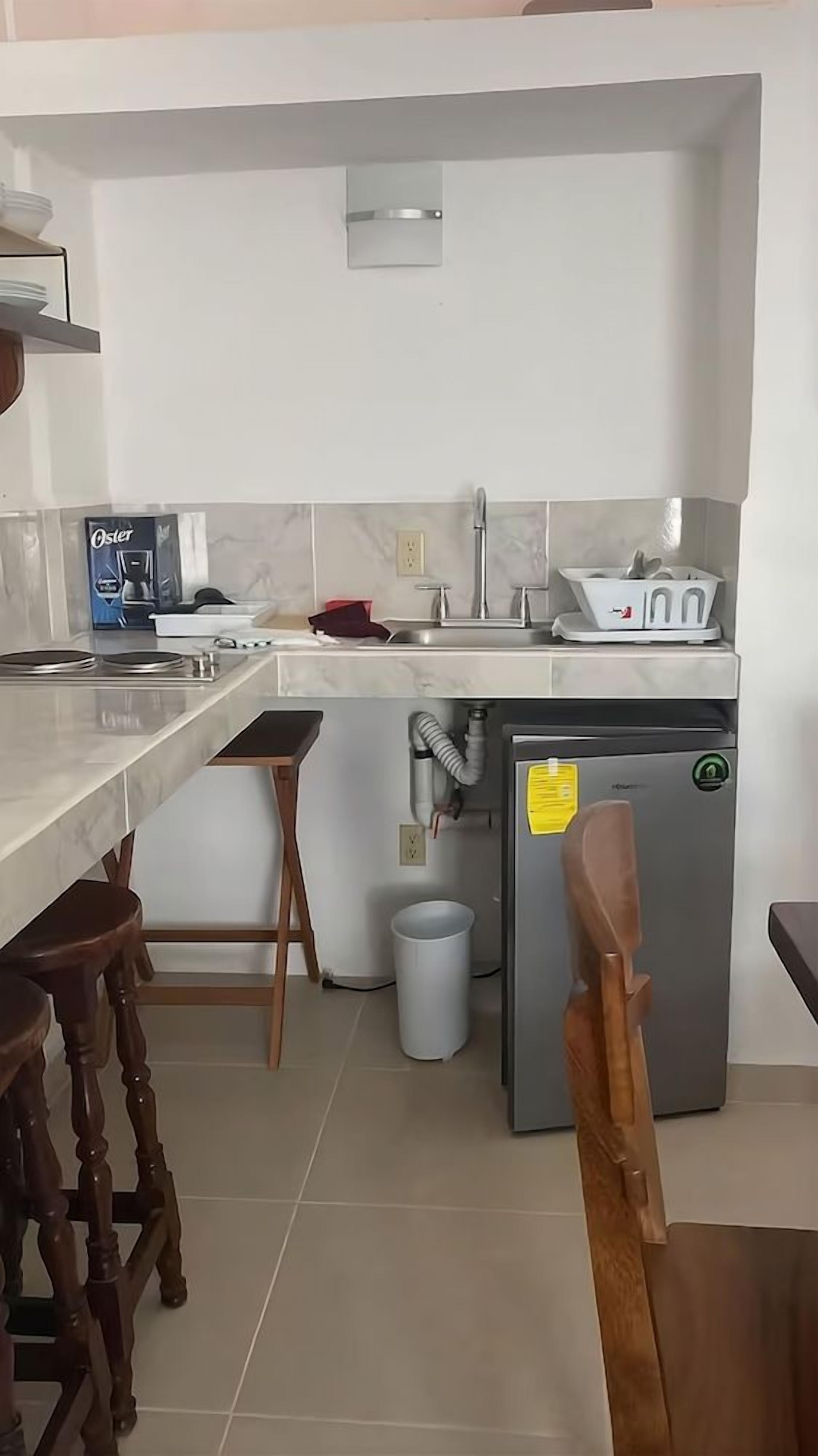 Cozinha com geladeira, pia e banquetas.
